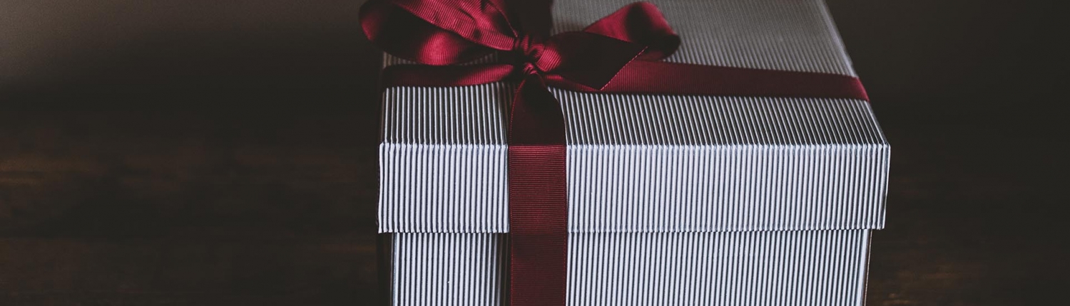 A white gift box with a red ribbon tied in a bow around it.