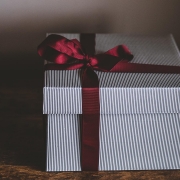 A white gift box with a red ribbon tied in a bow around it.