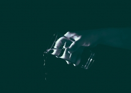 A black and while image of a hand pouring out a glass of water.