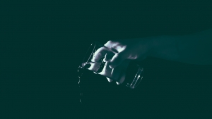 A black and while image of a hand pouring out a glass of water.