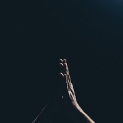 hands praying against a black background.